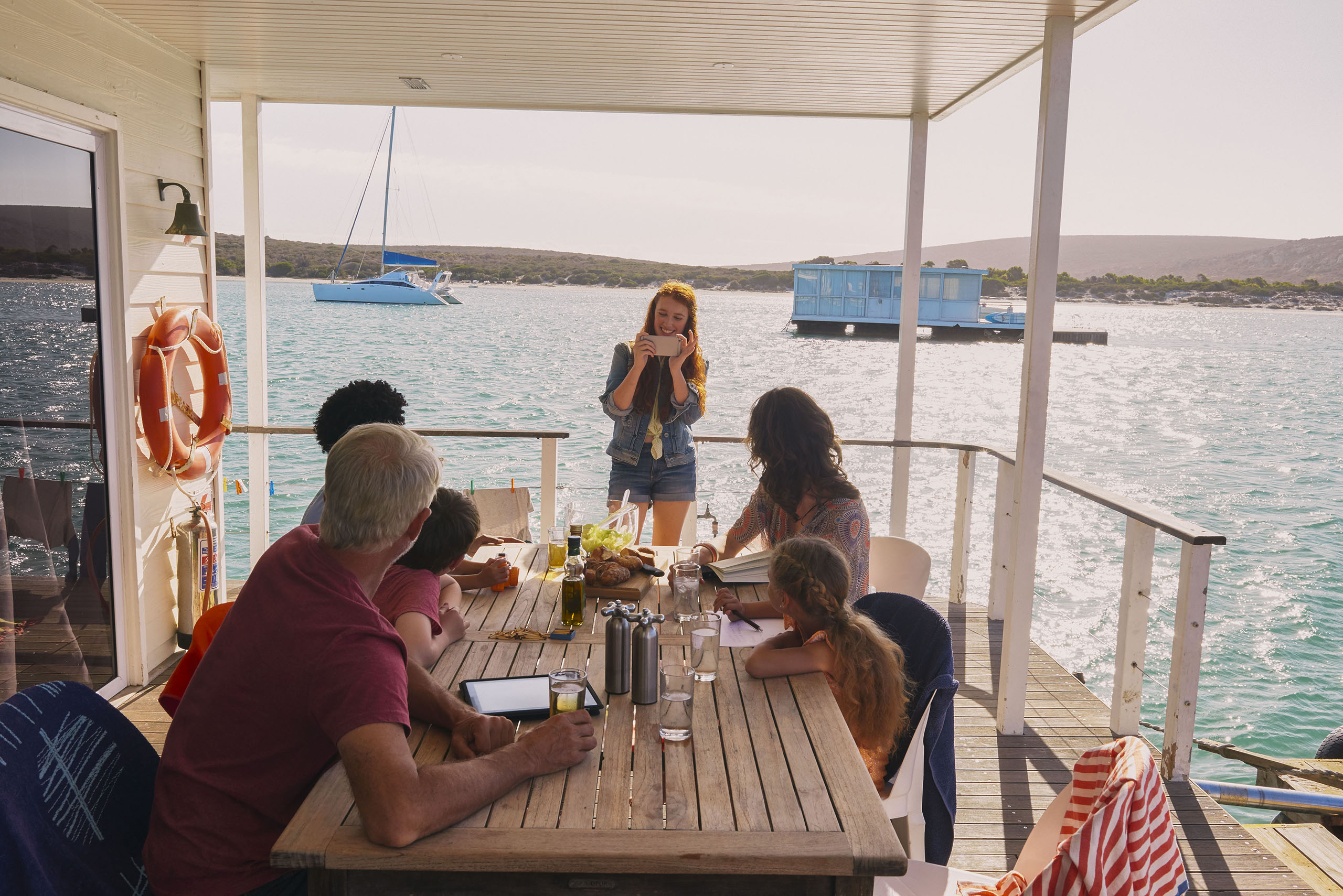 Family gathered at table on houseboat sun deck, Kraalbaai, South Africa